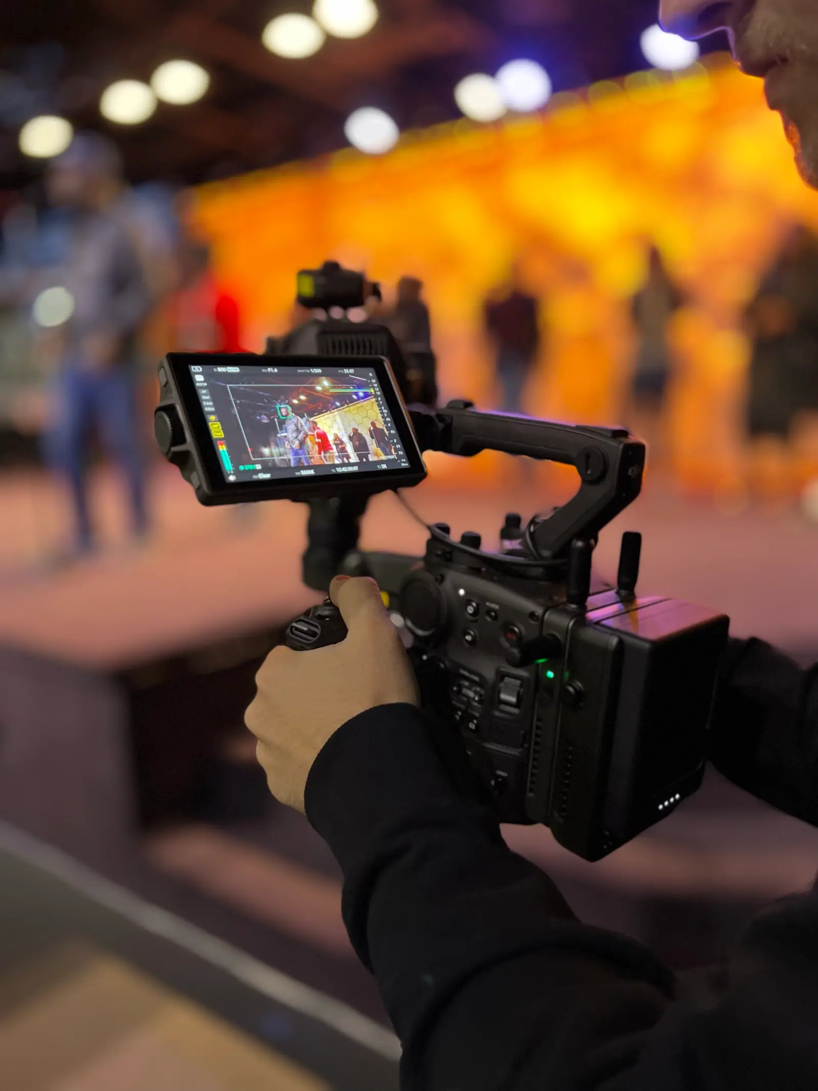 A handheld cinema camera covering a live event stage