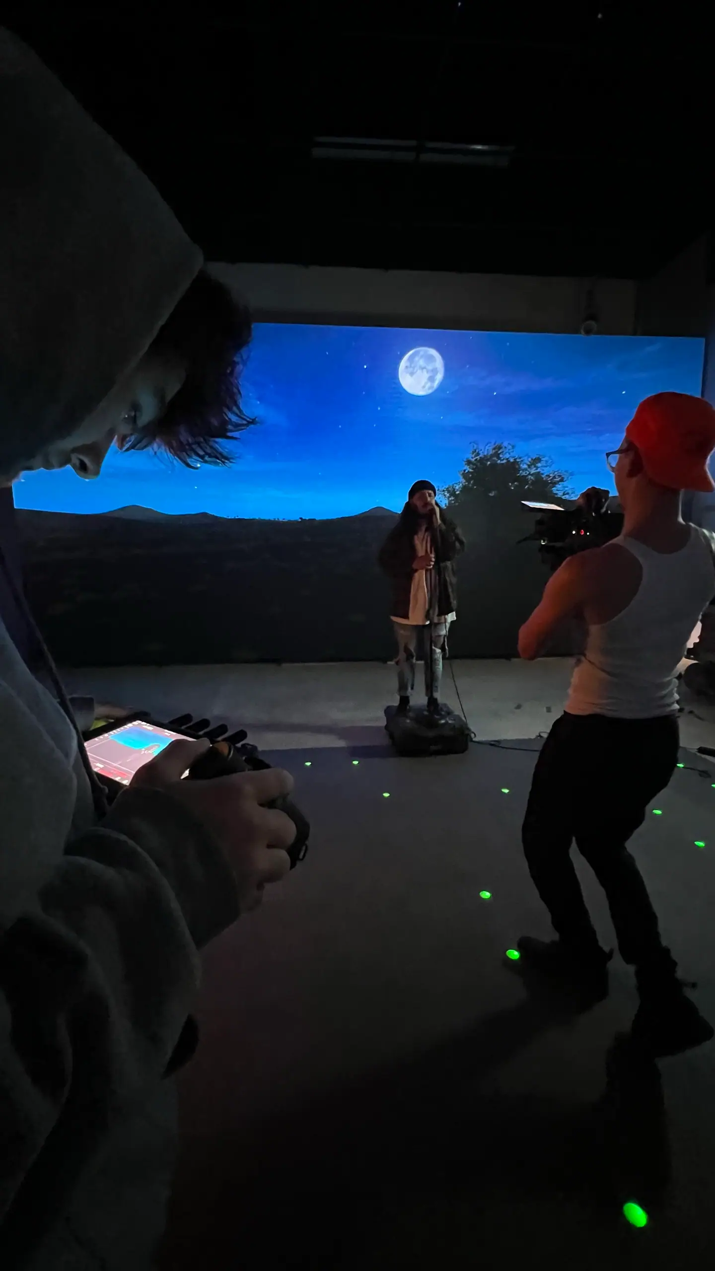 A performer on an LED volume under a moonlit sky, the camera operator in the foreground