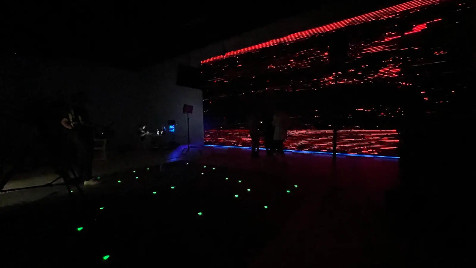 A red LED wall glowing across a dark stage, tracking markers on the floor