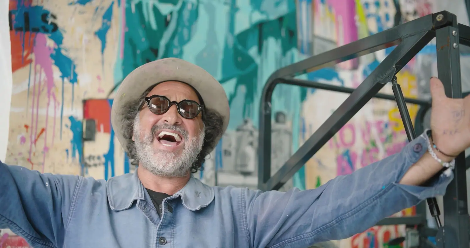 Mr. Brainwash, laughing, in front of his wall
