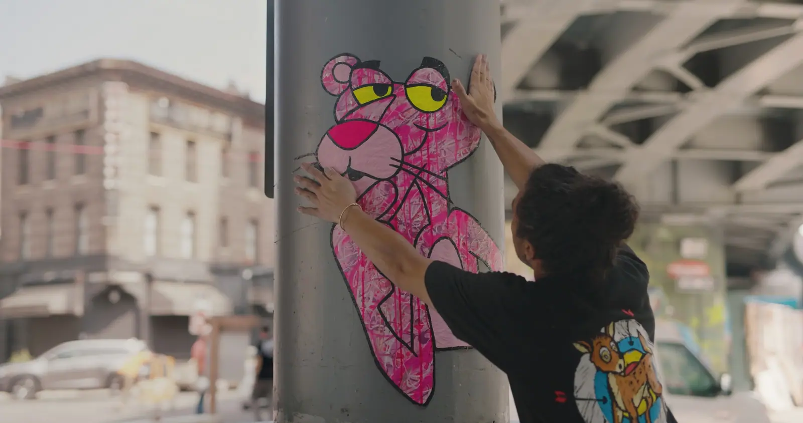 An artist pasting up a Pink Panther on a street column