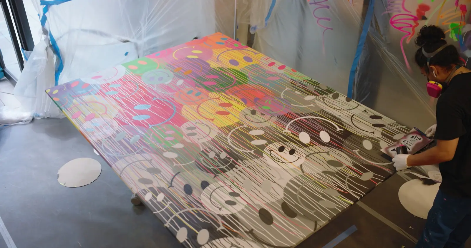A smiley-covered canvas on the floor of the lobby, under plastic